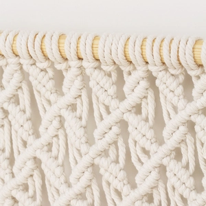 Handmade macrame wall hanging tapestry made of off-white cotton rope and natural wood