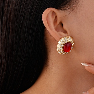 Boucles d'oreilles vintage dorées avec pierre rouge ovale et strass portées par un mannequin