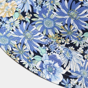 Detailed close-up of blue floral print and fine stitching on a wide-brim bucket hat