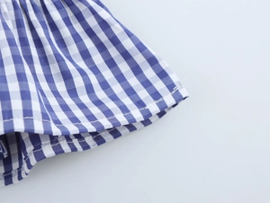 Détail du tissu à carreaux bleus et blancs avec une texture plissée sur le bord du vêtement