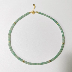 Detail of light green natural stone beaded necklace with gold spacers and lobster clasp