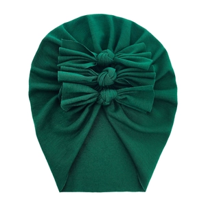 Detail of green soft cotton baby turban hat with three decorative bows on white background
