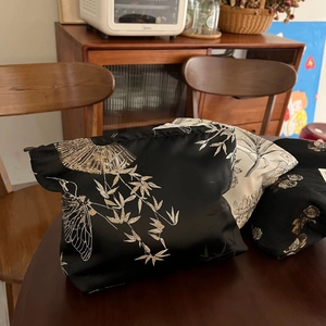 Detailed embroidery of bamboo and cicada motifs on black satin cosmetic bags
