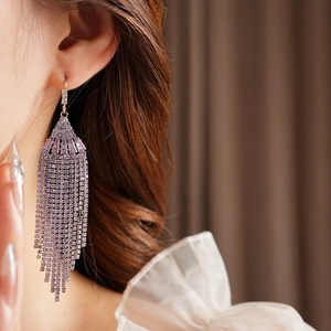 Close-up of purple tassel drop earrings with sparkling rhinestones worn by a model