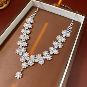 Exquisite silver necklace with crystal floral clusters on a brown jewelry box background