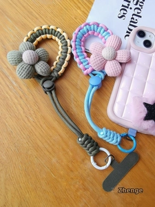 Detailed view of handmade woven phone wrist straps with plush flowers and secure clips