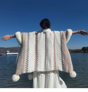 Ethnic knit shawl cloak with wavy stripes, faux rabbit fur collar, and pom-pom trim detail