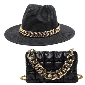 Detail of black straw fedora and quilted crossbody bag with chunky gold metal chains