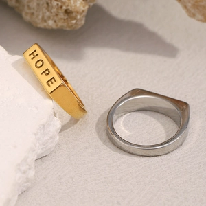 Makroaufnahme von minimalistischen Ringen in Gold und Silber mit HOPE-Gravur auf Stein