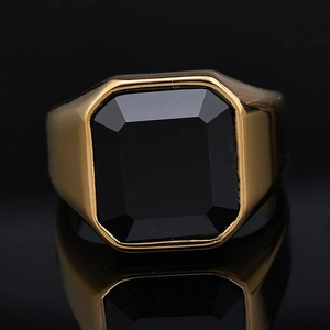 Macro shot of men's gold ring featuring a large octagonal faceted black gemstone with reflection