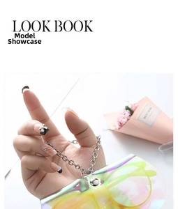 Detail of holographic PVC glasses pouch with silver metal chain held by a hand