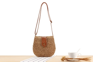 Detail of hand-woven paper straw bag with brown PU leather strap and gold metal clasp
