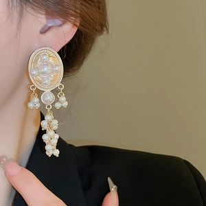 Close-up of vintage oval faux pearl tassel earrings with gold-tone accents on a model
