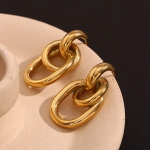Gros plan de boucles d'oreilles dorées sur une assiette beige et fond noir profond