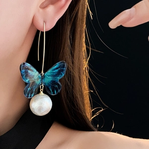 Detailansicht der blauen Schmetterling-Perlenohrringe mit Goldhaken am Model