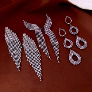 Detailed macro of luxury rhinestone teardrop tassel earrings on elegant red velvet background