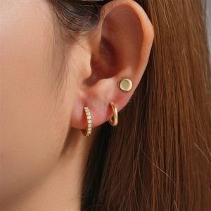 Close-up of gold geometric butterfly earring set with zircon accents on a model's ear