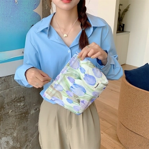 Close-up of tulip pattern canvas toiletry bag held by a model in a bright room