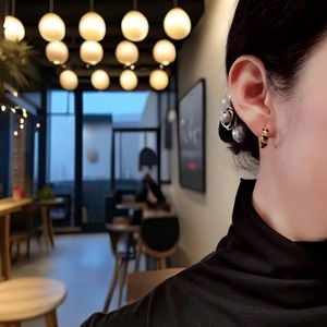 Close-up of golden leopard print hoop earrings and vintage pearl accents on model