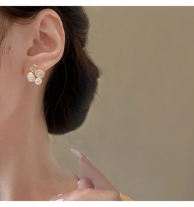 Detail of elegant gold earrings featuring freshwater pearls and sparkling zircons on ear