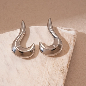 Close-up of polished silver geometric earrings on textured natural stone base