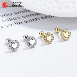 Detailed view of silver and gold heart stud earrings with sparkling zircon borders