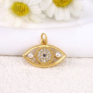 Detailed view of gold eye pendant featuring blue and white zircons and pearls