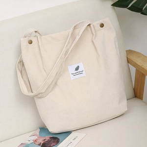 Detail of cream corduroy tote bag showing vintage metal ring and fabric brand label