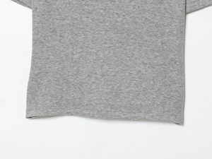 Close-up of light grey knit fabric showing premium stitching and hemline detail