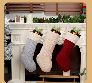 Detailed knit pattern of festive Christmas stockings in grey, cream, and red hanging on mantel