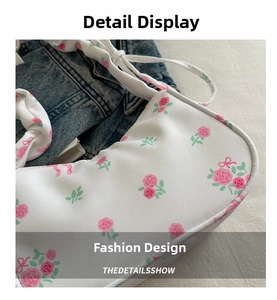 Close-up of white underarm bag featuring pink rose floral print and twill fabric texture