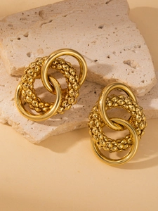 Close-up of golden oversized hoop earrings with polished and beaded texture on stone