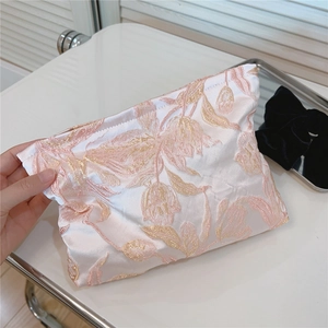 Detailaufnahme der rosa Tulpenstickerei auf einer luxuriösen Satin-Kosmetiktasche