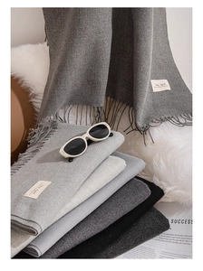 Detail of soft solid color scarf showing fine texture, fringe, and a woven brand tag