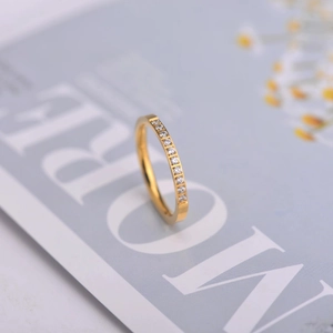 Primo piano di un anello minimalista in oro con zirconi incastonati su una rivista