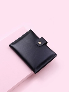 Close-up of black PU leather short wallet with gold snap button on a pink pedestal