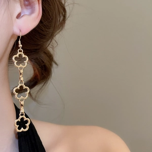Detail of elegant gold hollow flower tassel earrings worn by a model in soft natural lighting