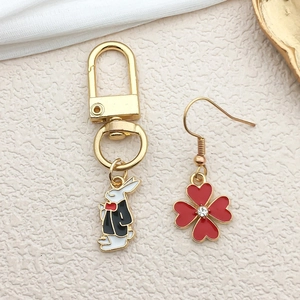 Detail of bunny charm in black suit and red clover earring with crystal inlay