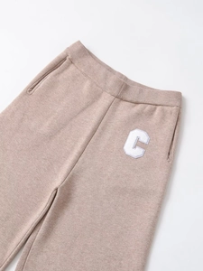 Detail of oatmeal knit trousers with white letter C embroidery and ribbed elastic waist