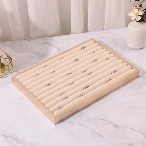 Detail of beige velvet jewelry display tray with champagne gold frame on marble surface