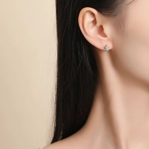 Golden sea turtle stud earrings with blue gemstone and white zircon on ear