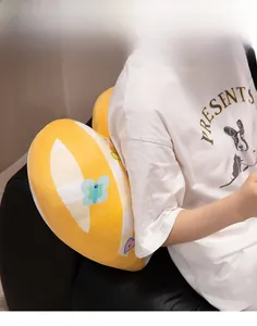 Detailed view of a yellow heart-shaped plush pillow with blue butterfly patterns on a sofa