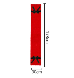 Macro view of plush red Christmas table runner with green bow knot and faux fur texture