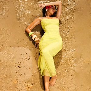 Elegant yellow mesh strapless dress with side slit worn by model on a sunny beach