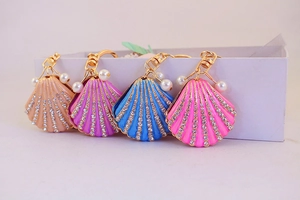 Detail of four colorful enamel seashell keychains with rows of rhinestones and small pearls