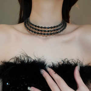 Detail of elegant black multi-layer beaded choker necklace on model with feathers