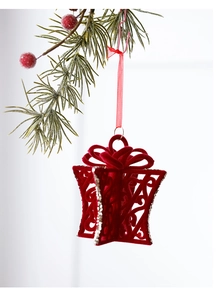 Detail of red flocked gift box Christmas ornament with gold glitter hanging on pine branch