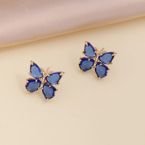Elegant gold butterfly earrings with blue cubic zirconia on beige silk background
