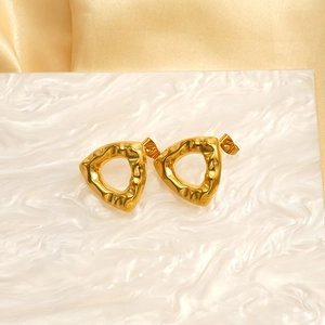 Boucles d'oreilles triangles dorées minimalistes avec texture martelée sur fond marbre