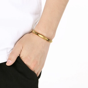 Polished gold watchband-style link bracelet with rectangular flat ID bar on a wrist